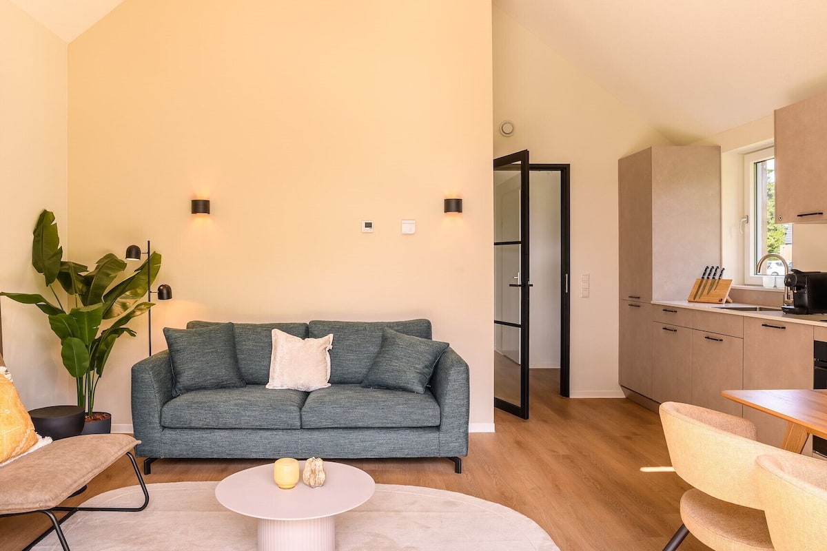A modern living room with a grey sofa, a round coffee table, and a large plant.