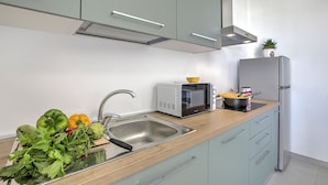 A modern kitchen with a stainless steel sink, a microwave, and a refrigerator. - Boutique Apartament With Pool and Padel Court (Galatina)