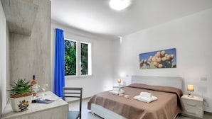 A modern bedroom with a bed, bedside tables, a desk with a plant, and a window with curtains. - Boutique Apartament With Pool and Padel Court (Galatina)