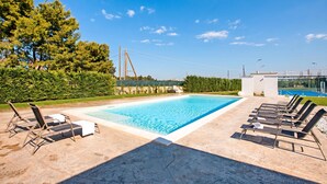 A rectangular swimming pool with lounge chairs and a white structure in the background. - Boutique Apartament With Pool and Padel Court (Galatina)
