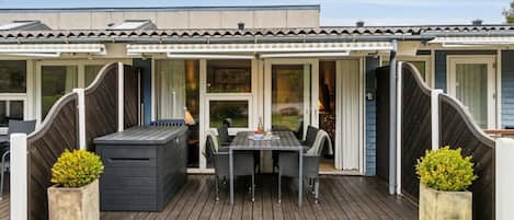 A mobile home with a deck, outdoor seating, and a small garden area.