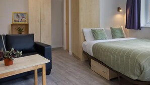 A bedroom with a bed, bedside tables, a wardrobe, and a small table with a plant. - Student Only Knoll Court (Newcastle-upon-Tyne)
