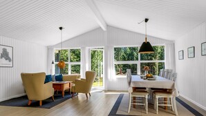Una habitación amplia con una mesa de comedor y sillas, un sofá y un ventanal con vistas al exterior.