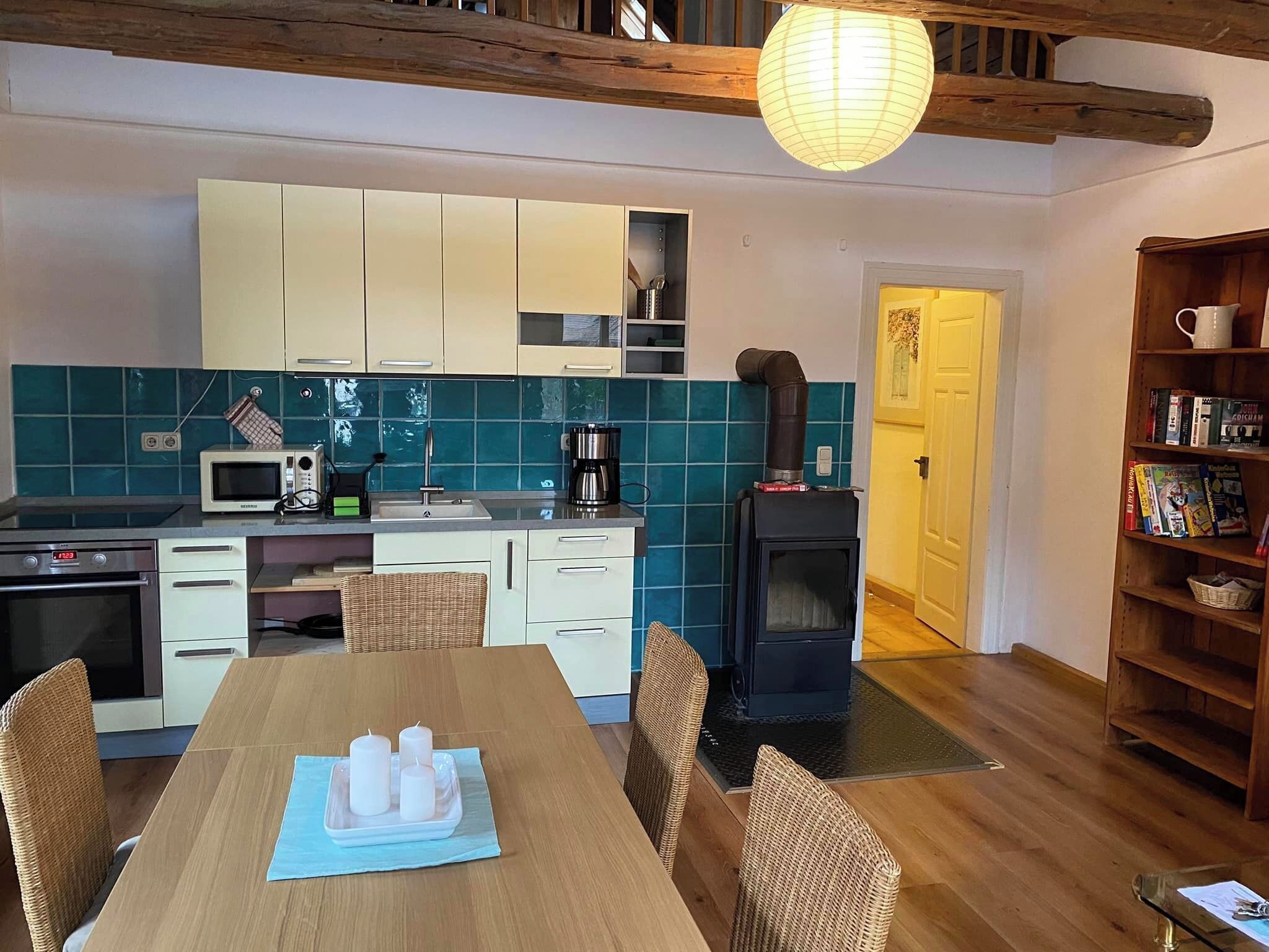 A cozy kitchen with white cabinets, a microwave, a coffee maker, and a wood-burning stove.
