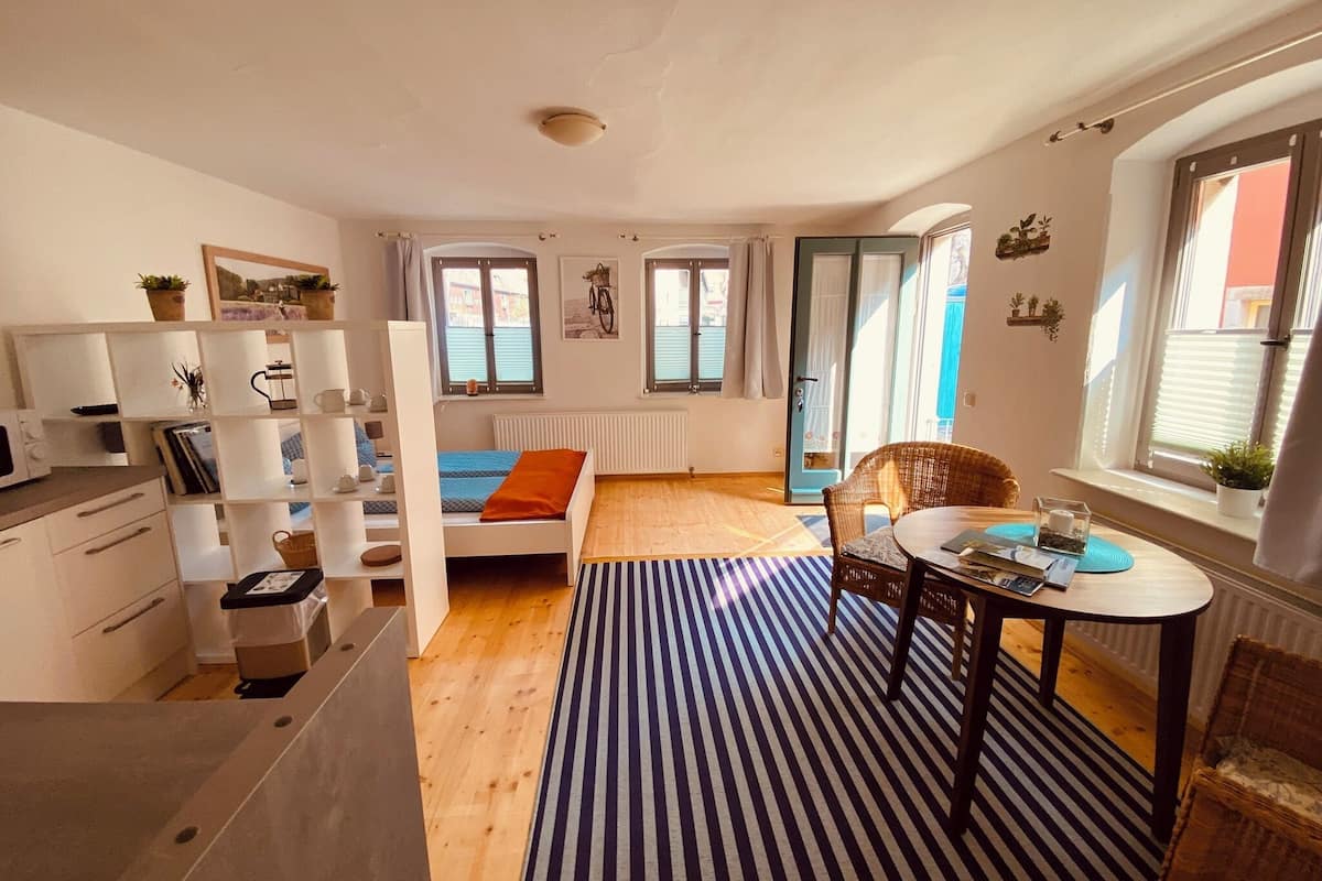 Ein kompakter Wohnraum mit Bett, Essbereich, Küche und einer kleinen Sitzecke.
