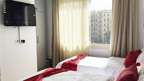 A hotel room with two beds, a TV mounted on the wall, and a window with curtains. - marhaba inn (Cairo)