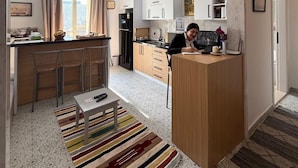 A modern kitchen with a central island, a dining area with chairs, and a kitchen counter. - marhaba inn (Cairo)