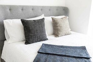A bed with a grey upholstered headboard, white and grey pillows, and a folded grey blanket. - Spacious 3BR Garden House near Central Doncaster (Doncaster)