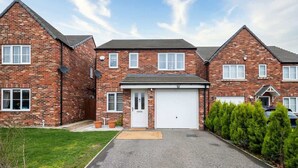A two-story brick house with a front garage, a well-maintained lawn, and a driveway. - Spacious 3BR Garden House near Central Doncaster (Doncaster)