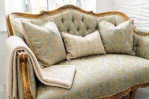 Un canapé de style vintage, doté d’un dossier capitonné et d’un cadre décoratif.