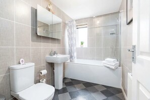 Une salle de bain moderne équipée de toilettes, d’un lavabo et d’une baignoire.
