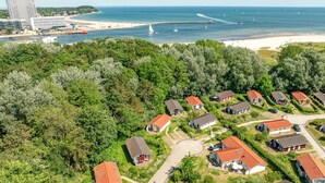 An aerial view of a coastal area with a row of houses, a beach, and a pier. - Pulverhorn vacation home 03 (Lübeck-Travemünde)