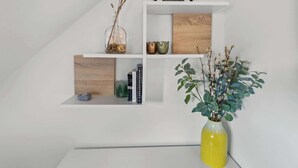 A white wall with three white shelves, each holding various decorative items. - Central Exeter 3BR | Walk Everywhere (Exeter)