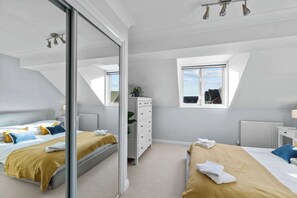 Relax in a serene bedroom with a large bed, bedside tables, and a dresser, offering a peaceful retreat with a view.