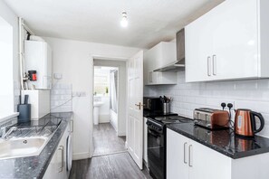 Kitchen features a sink, stove, and toaster, with a bathroom nearby, including a toilet and shower.