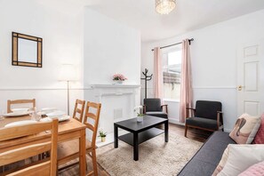 Relax in this stylish living room with a fireplace, dining table, and comfortable sofa.