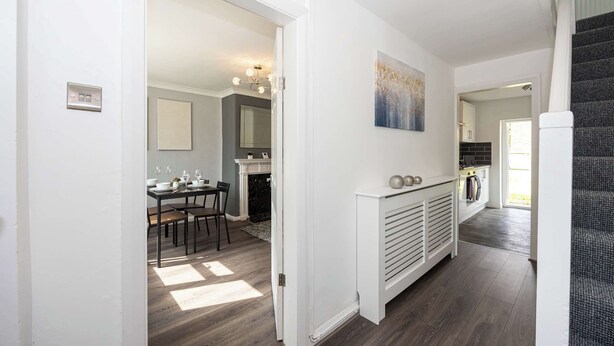 A modern kitchen with a built-in oven, a dining area with a table and chairs, and a staircase leading to another level. - Charming Liverpool House | Garden & Comfort (Liverpool)