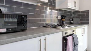 A modern kitchen with white cabinets, a black cookware station, and grey tiled backsplash. - Charming Liverpool House | Garden & Comfort (Liverpool)