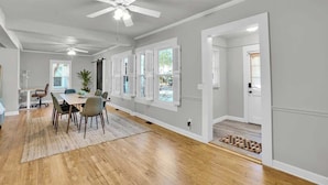 A spacious dining area with a high ceiling fan, wooden flooring, and a dining table set for six.