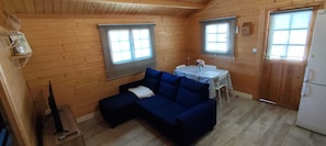 Ein gemütliches Blockhaus mit einem blauen Sofa, einem kleinen Tisch mit einer Vase und einem Kühlschrank.