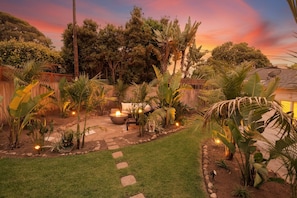 A garden with a fire pit, stone pathway, and various plants.
