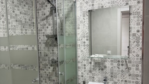 A bathroom with a shower, a sink, and a mirror. - Hotel B and B Suites (Benidorm)