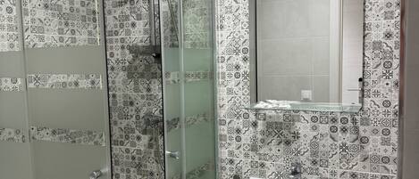 A bathroom with a shower, a sink, and a mirror.
