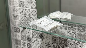 A bathroom with patterned tiles and a glass shelf holding a packet labeled "MXM'S". - Hotel B and B Suites (Benidorm)