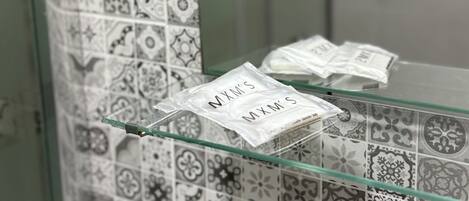 A bathroom with patterned tiles and a glass shelf holding a packet labeled "MXM'S".