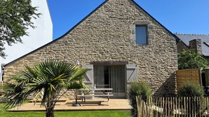 A stone house with a wooden deck, a small window, and a door. - Charm in the heart of the village: house with sunny garden close to the sea (Arradon)
