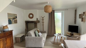A modern living room with a sofa, a television, and a fireplace. - Charm in the heart of the village: house with sunny garden close to the sea (Arradon)