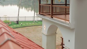 Un bâtiment doté d’un balcon donnant sur un lac paisible et des palmiers.