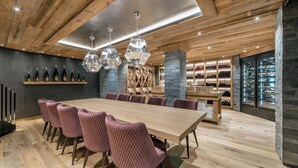 Un espace de restauration moderne avec une longue table en bois, des chaises à revêtement rose et des suspensions hexagonales.