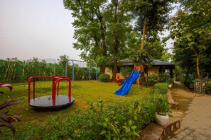 A playground with a swing set, a slide, and a small shelter. - Ashoka Tiger Trail By VistaLux (Ramnagar)