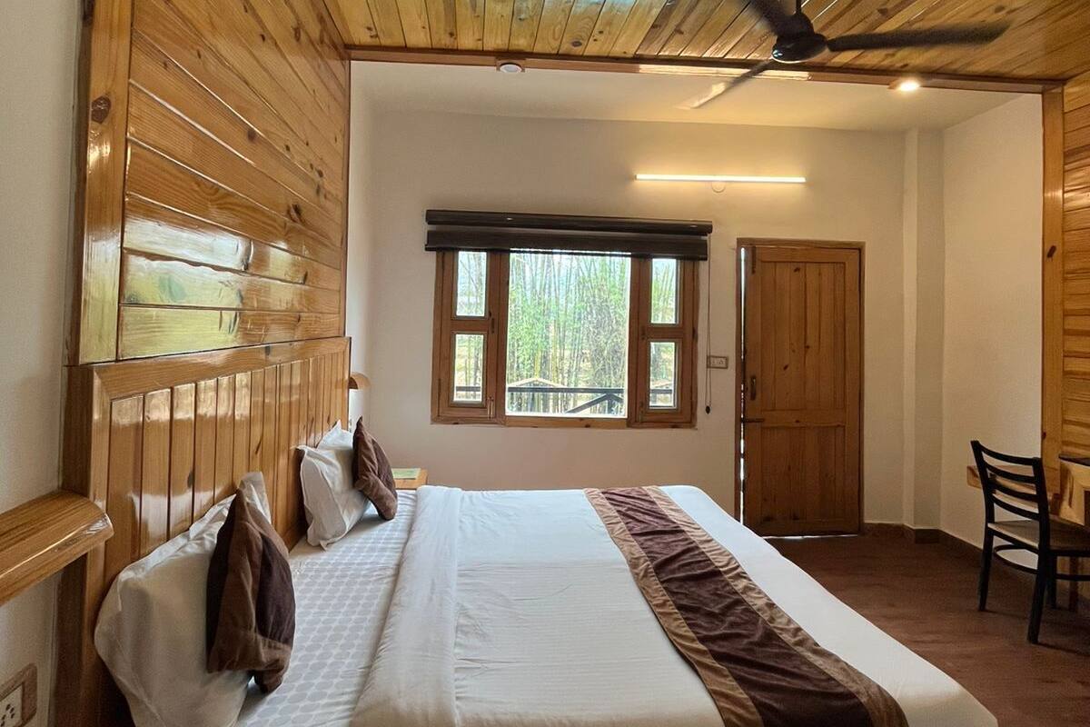 A wooden-paneled bedroom with a bed, a desk, and a chair.