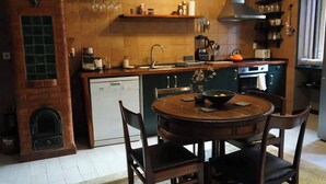 Una cocina con una mesa de madera, sillas, lavavajillas y una chimenea de ladrillo.