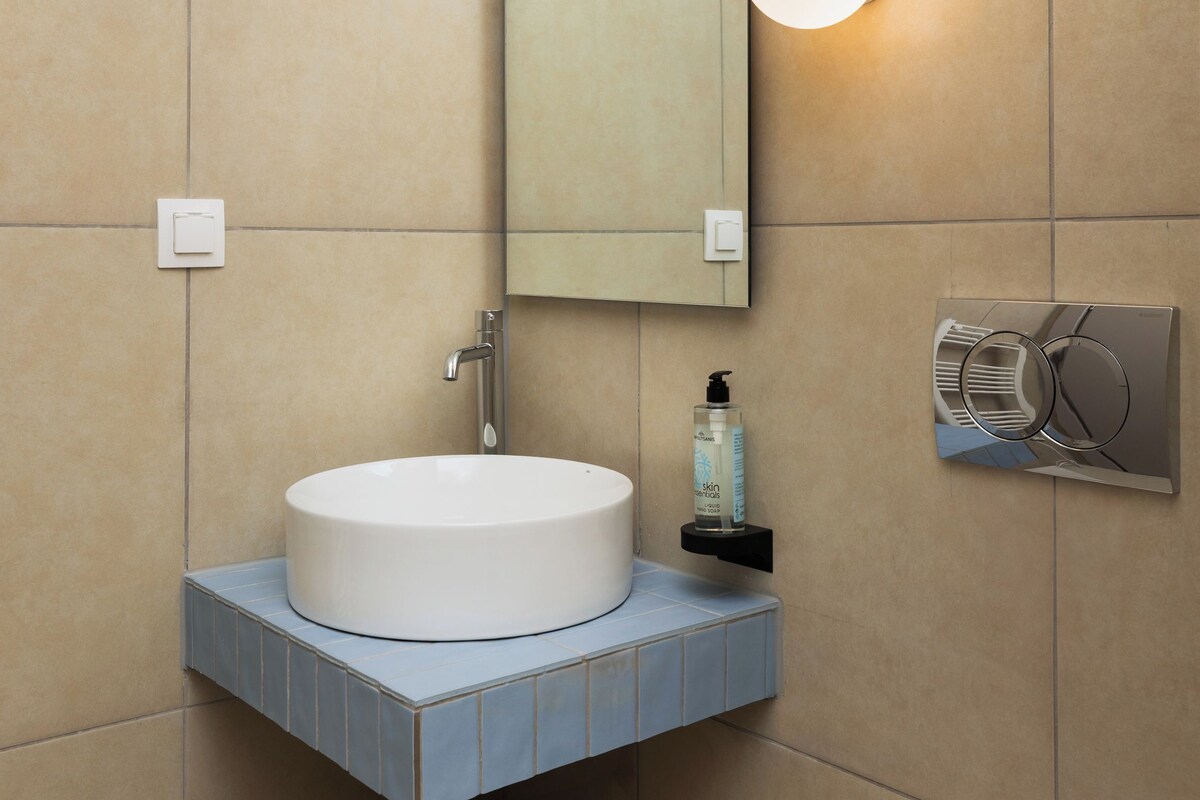A modern bathroom with a white sink, a mirror, and a toilet.