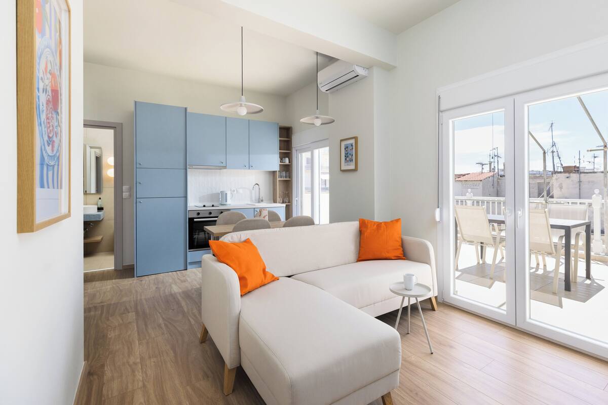 En moderne stue med en hvid sofa, orange puder og et lille rundt bord.