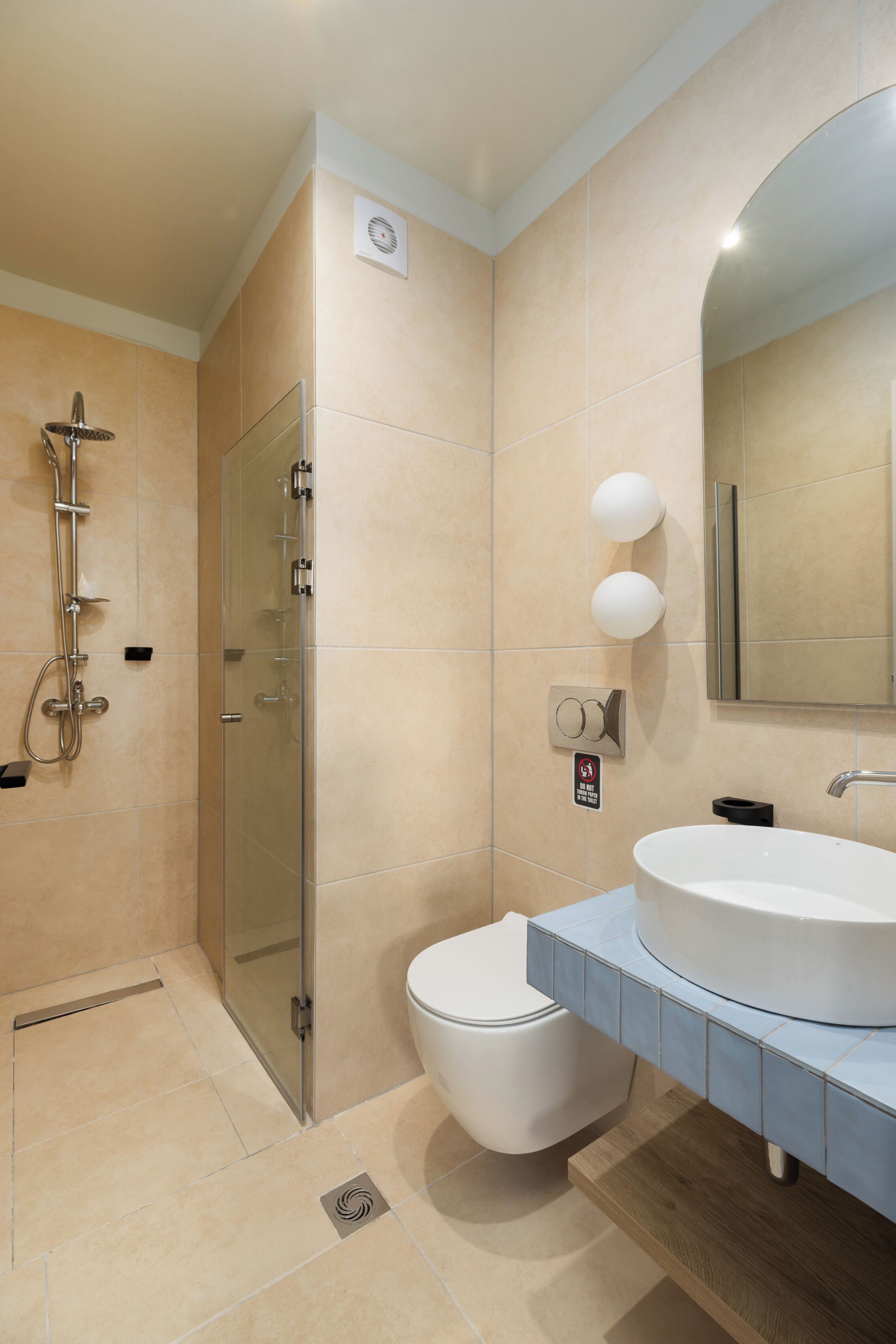 Een moderne badkamer met een glazen douchecabine, een wit toilet en een wastafel met een grote spiegel.