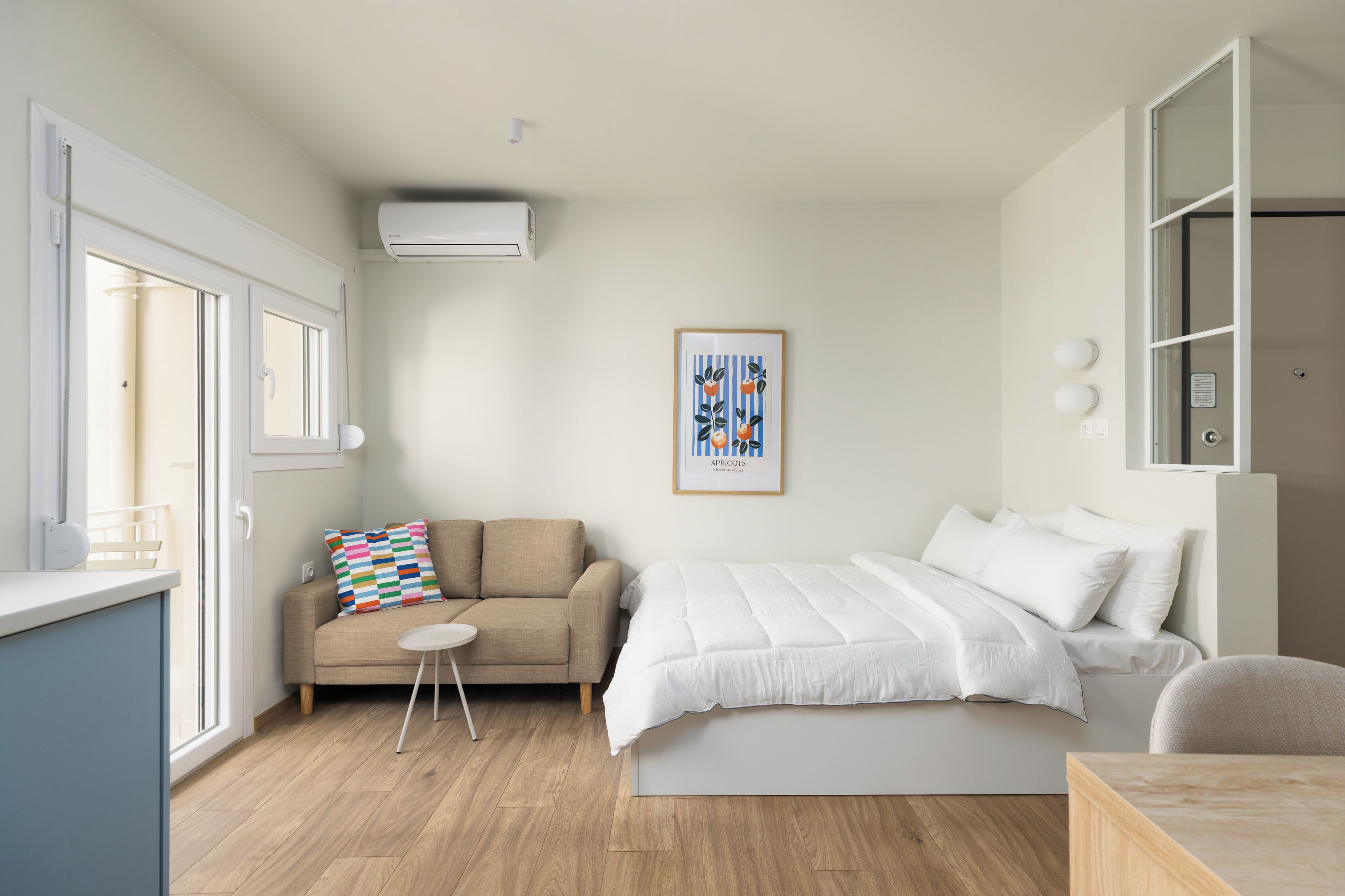 A modern bedroom with a bed, a sofa, a small table, and a framed picture on the wall.