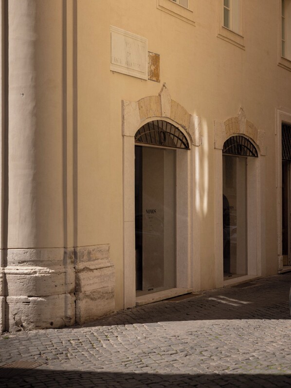 A building with arched doorways and a cobblestone street. - Nomos Hotel (Rome)