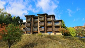 Un immeuble à plusieurs étages doté de balcons, entouré d’arbres et d’herbe.