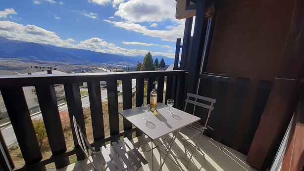 Un balcon avec une table et des chaises, donnant sur un paysage montagneux.