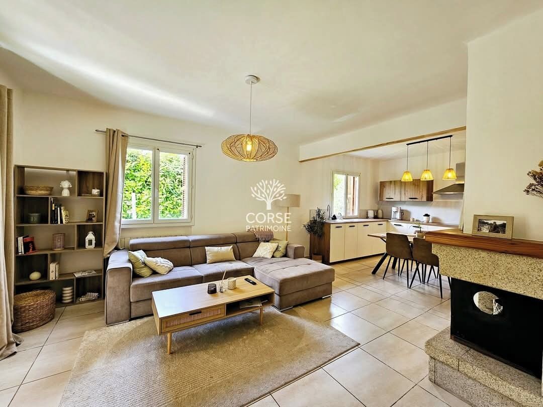 A modern living room with a sofa, coffee table, and a kitchen area with a dining table and chairs.