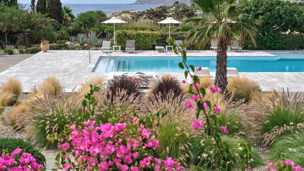A pool area with a clear view of the sea and mountains in the background.