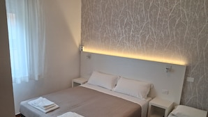 A hotel room with a large bed, two bedside tables, and a wall with a tree pattern. - Hotel Conca d'Oro (Rimini)