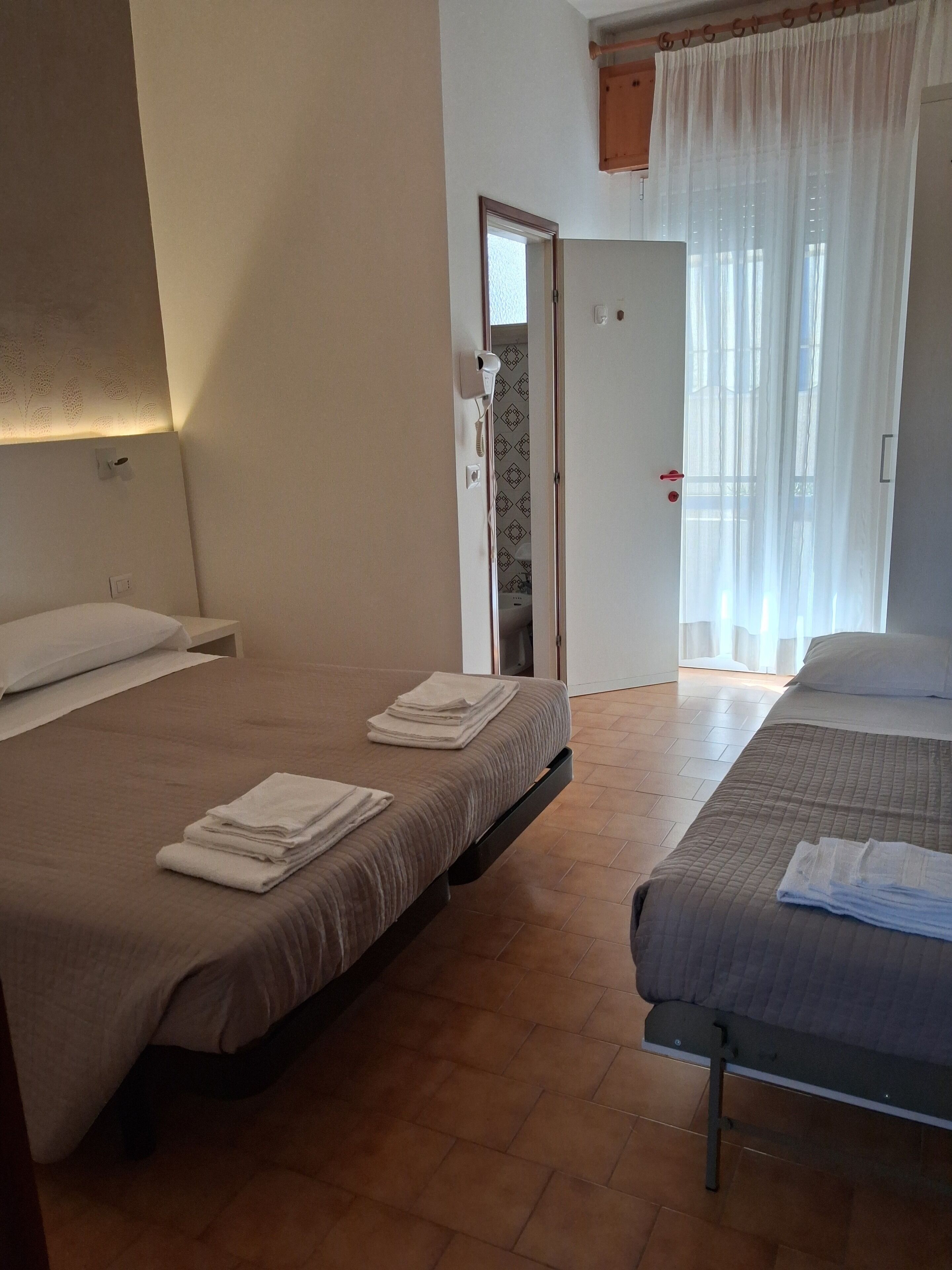 A hotel room with two beds, a bathroom, and a door leading to another room.