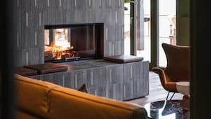 Een moderne woonkamer met een ingebouwde open haard, een bank en een glazen deur naar een buitenruimte.