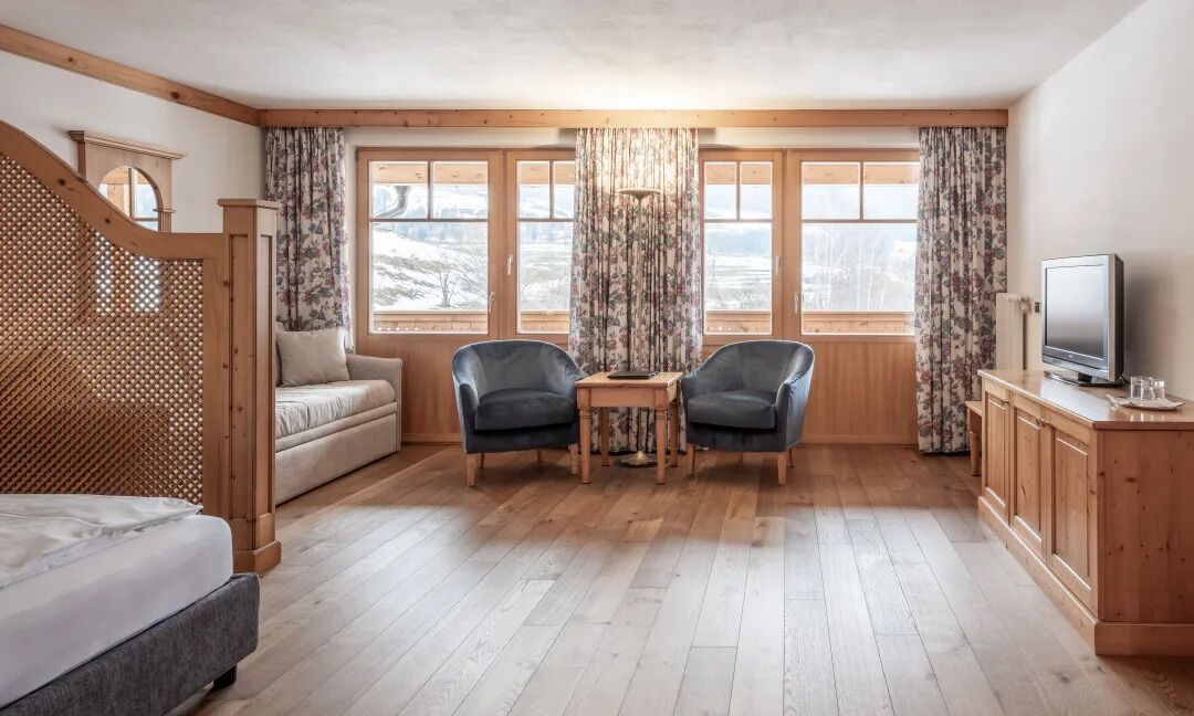 Une pièce confortable avec un lit, deux fauteuils, une petite table et un téléviseur.