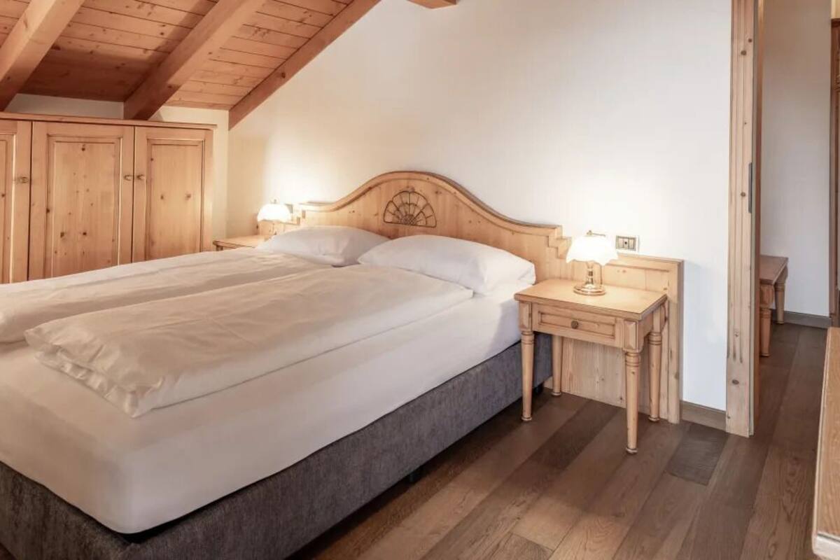 Quarto com uma cama grande, cabeceira de madeira, mesas de cabeceira e um guarda-roupa.